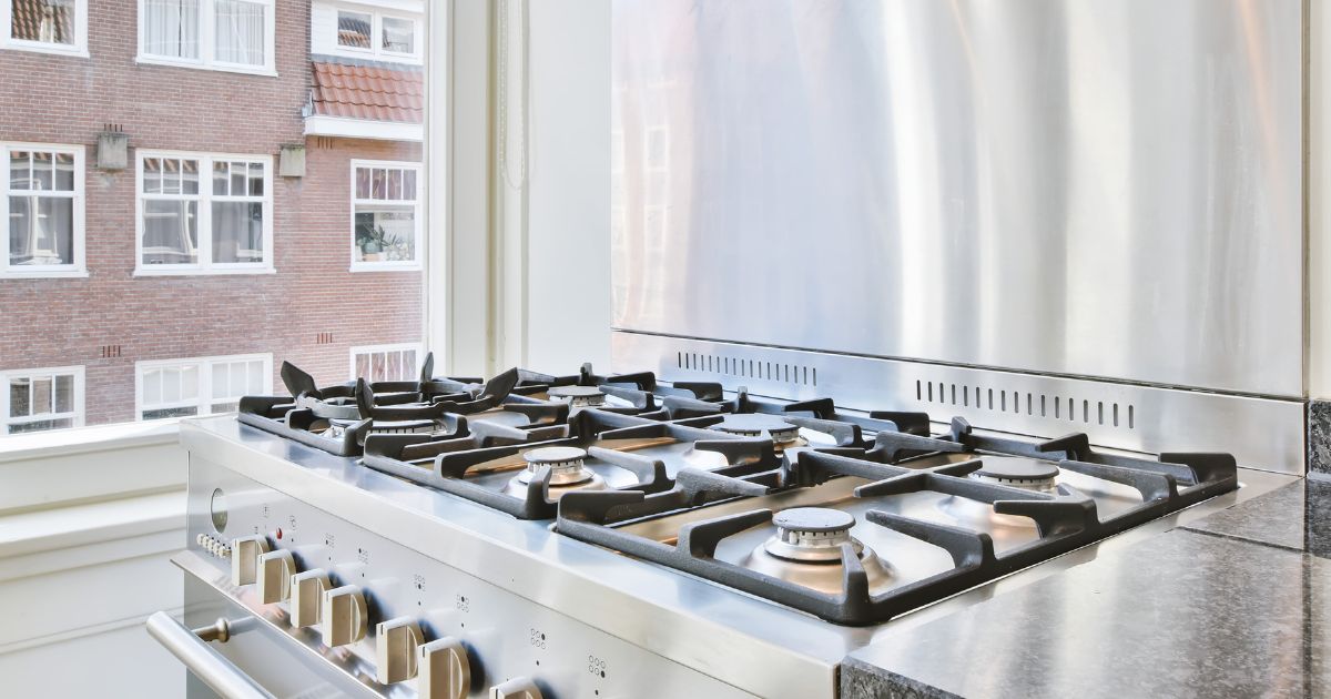 A sparkling clean gas range next to a window with no curtains.