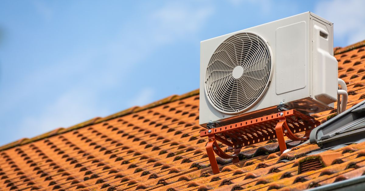 A heat pump installed on a terra cotta roof, shot during a bright sunny day.