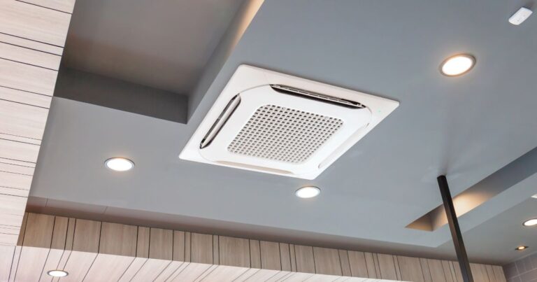 An aircon duct on a gray ceiling with soft corner lights in the corners of the said ceiling.