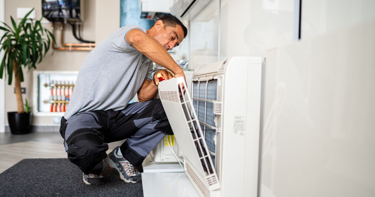 A man reaching out into something from an open heater in a living room.