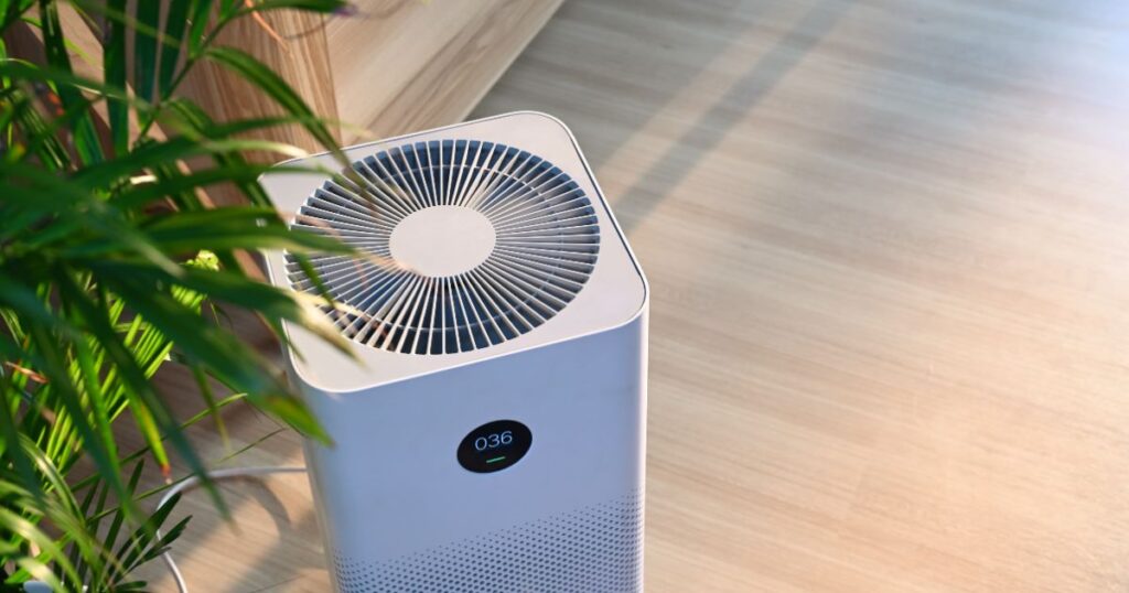 High angle shot of an air purifier placed beside a pot of indoor plants. 