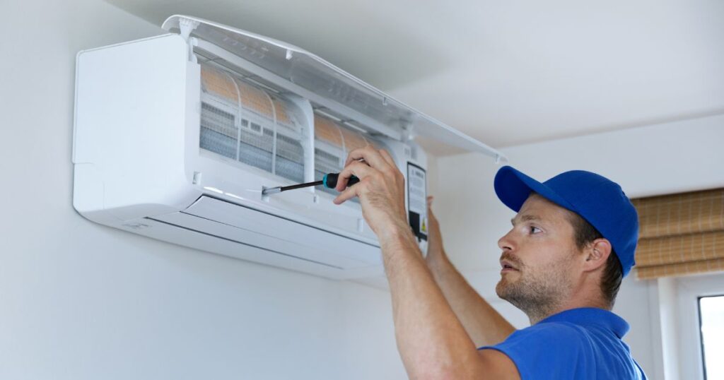 A man securing a screw of an open split type air conditioner. 