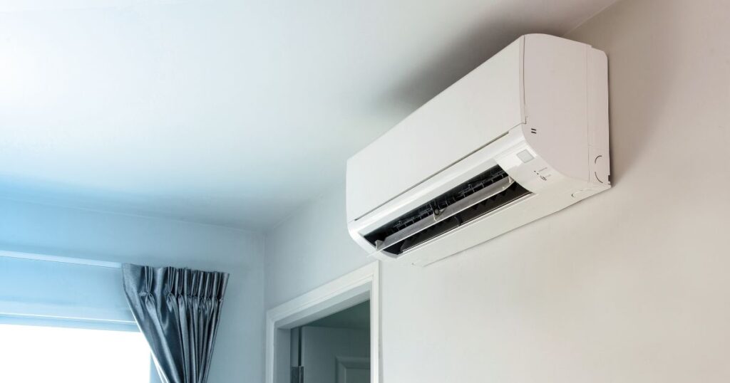 A split type air conditioner mounted on a white wall. 