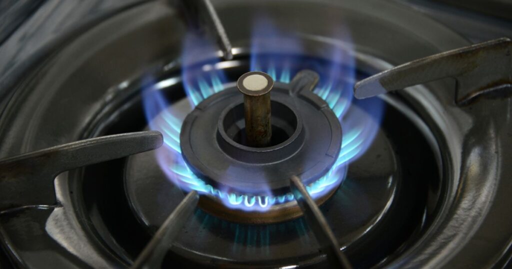 High angle shot of a gas range that has been turned on and churning out blue flames.