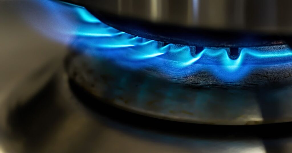 Closeup shot of a stove top turned on and a pot placed over it. 