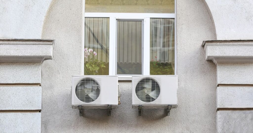 Two heat pumps beneath a window.