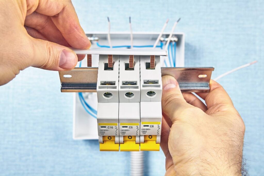 Hands holding both sides of a Residual Current Device installed in a wall. Installing RCD's is one of the Essential Guides to Electrical Safety at Home. It's a tip Every Household Should Know.
