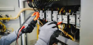 A person performing maintenance works on an electrical wiring system.
