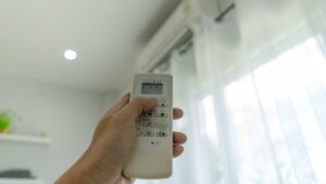 A hand holding an air conditioner remote upwards.