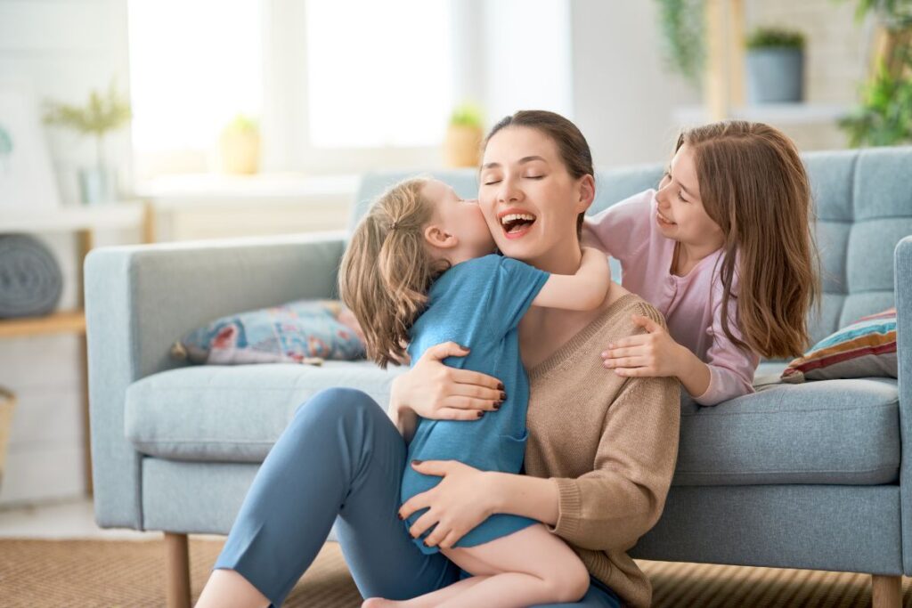 A mother spending her time with her 2 children while in a living room with childproof electrical sockets.