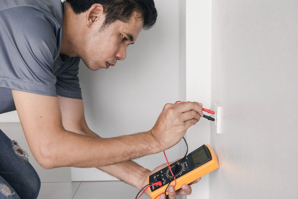 A licensed electrician performing fault finding methods on a electrical socket in a home. Investing in fault finding services is one of the ways to childproof electrical sockets at home.