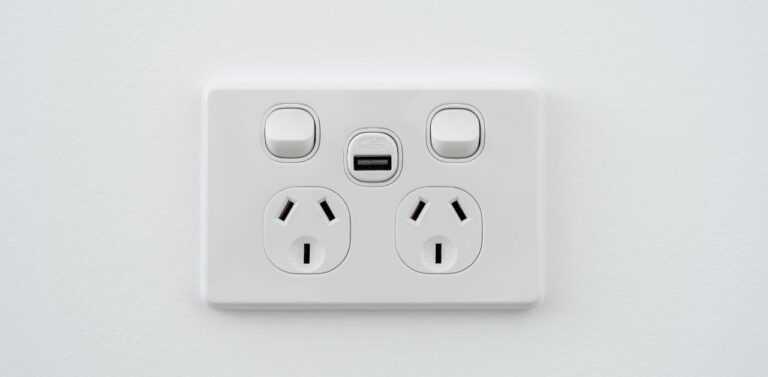 An electrical socket on a white wall. Covering these sockets are one of the ways to childproof electrical outlets at home.
