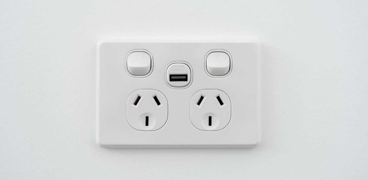 An electrical socket on a white wall. Covering these sockets are one of the ways to childproof electrical outlets at home.