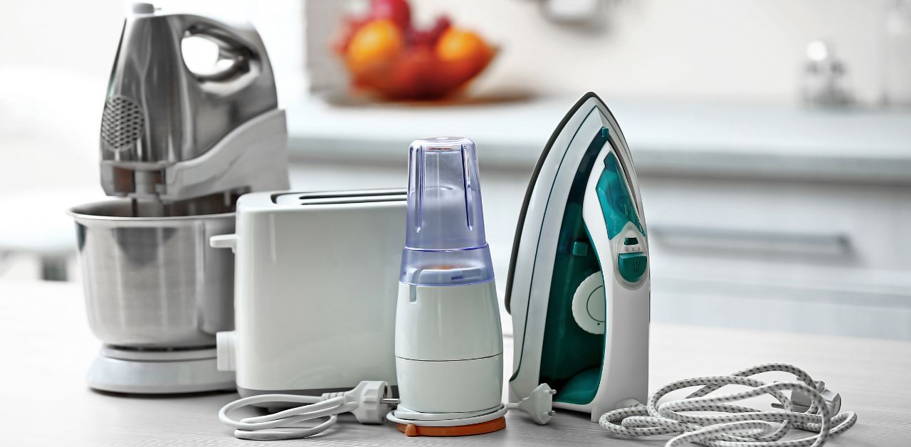 A kitchen mixer, a flat iron, a toaster, and a spice blender, on a kitchen surface.