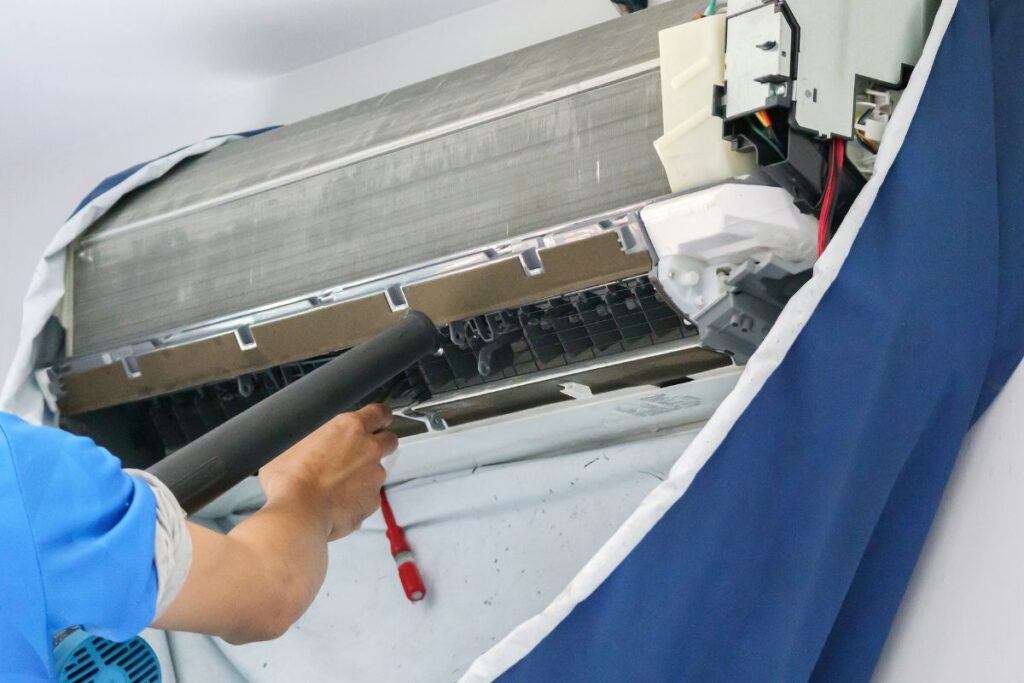 A person cleaning a split type air conditioner. The true value of a professional air conditioning service lies on how long an air conditioning unit lasts with mimimal breakdowns.