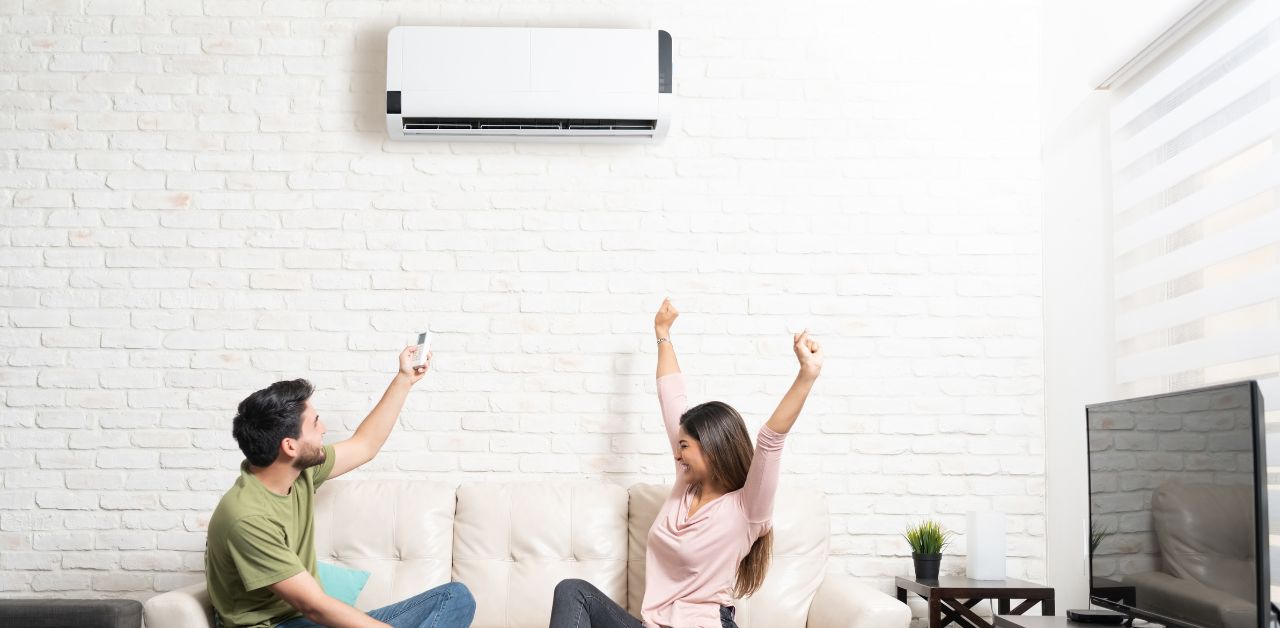 A man and a woman happily sitting in a cooled room with a split type ac with proper refrigerant levels.