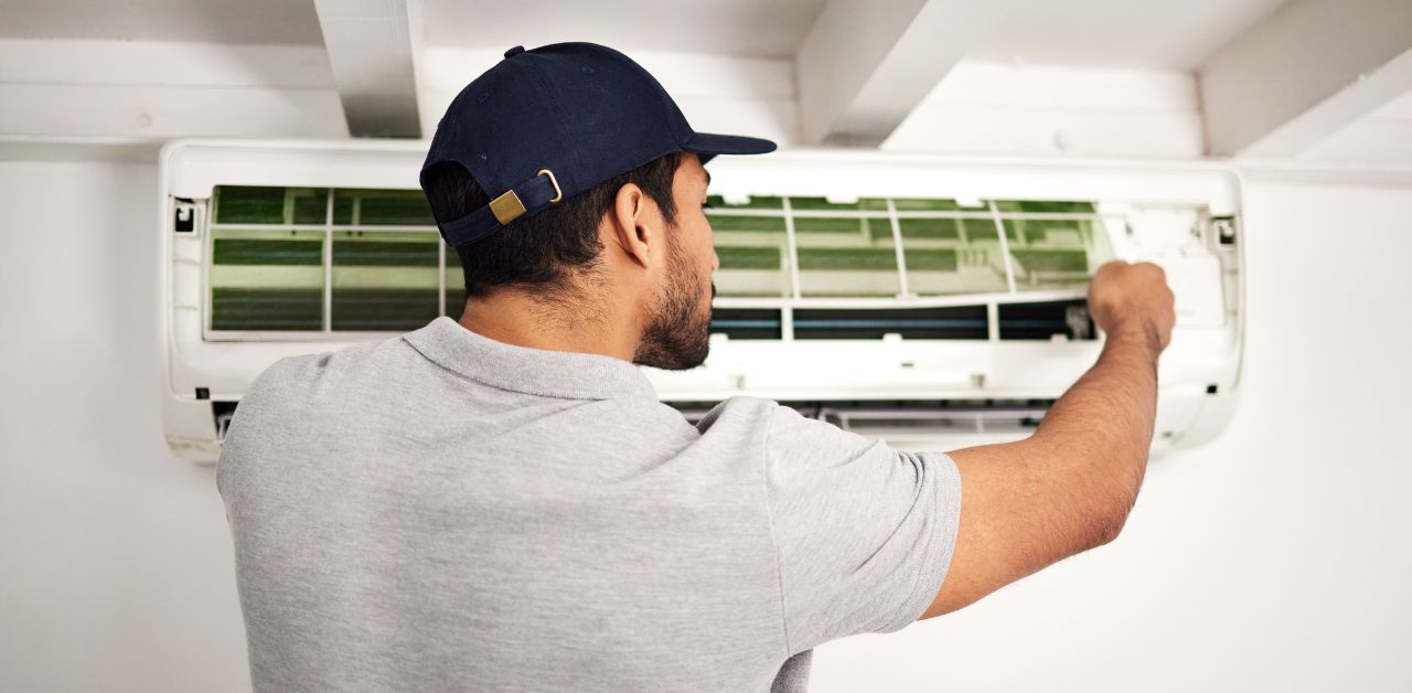 A man performing an annual AC maintenance on a split type unit.