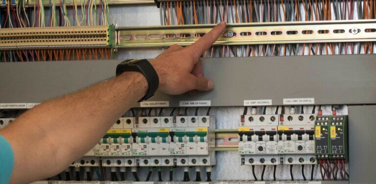A hand pointing to a wire on a mechanical board. This image hints at how Residual Current Devices work.