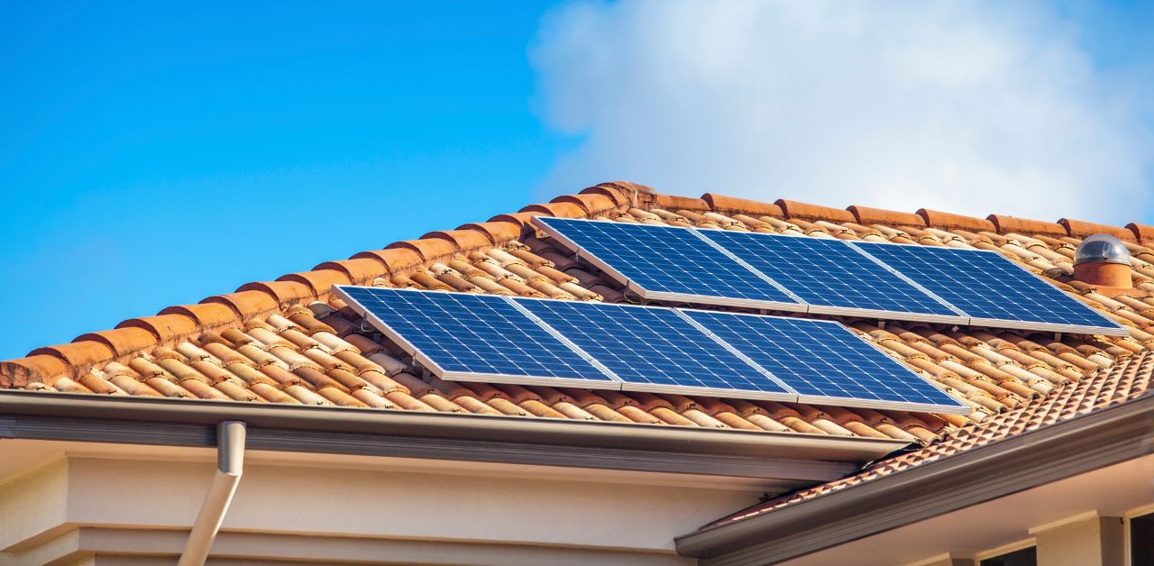 A roof with solar panels on a bright sunny day. This article answers the question: Is It Worth Adding Solar to Your Heating and Cooling System?