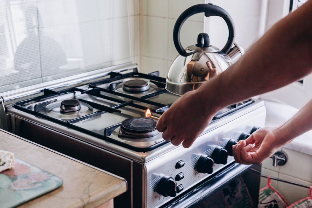 A person lighting a gas stove for cooking. This article tackles The Shift Away from Gas in Australia and What It Means for Your Home.